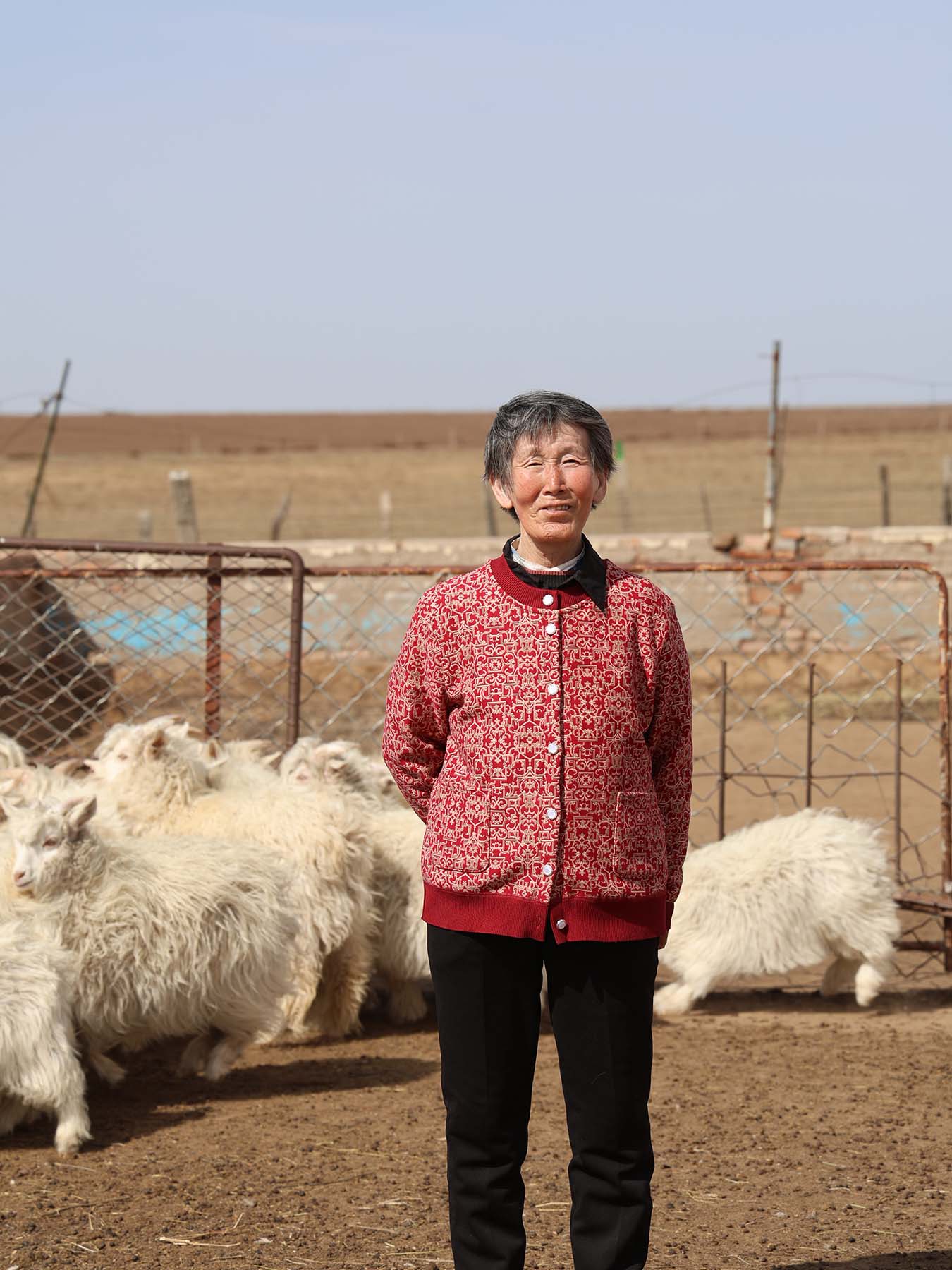 goat farmer in red jacket